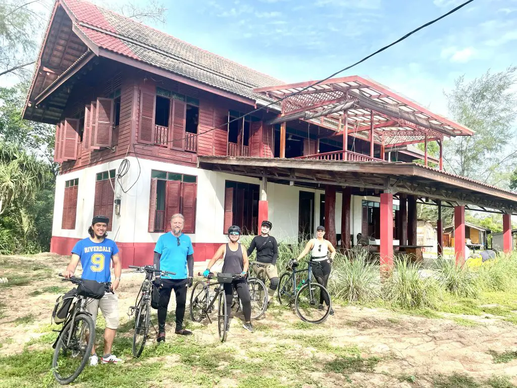 me standing in front of a old Malaysian house with my family and bicycles, giving them all tips for beginner cyclists!